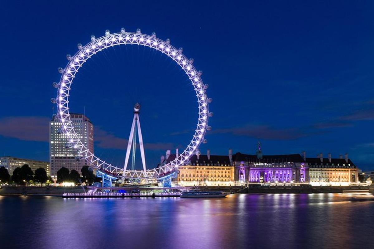 London Eye upplýst á nóttunni með byggingum