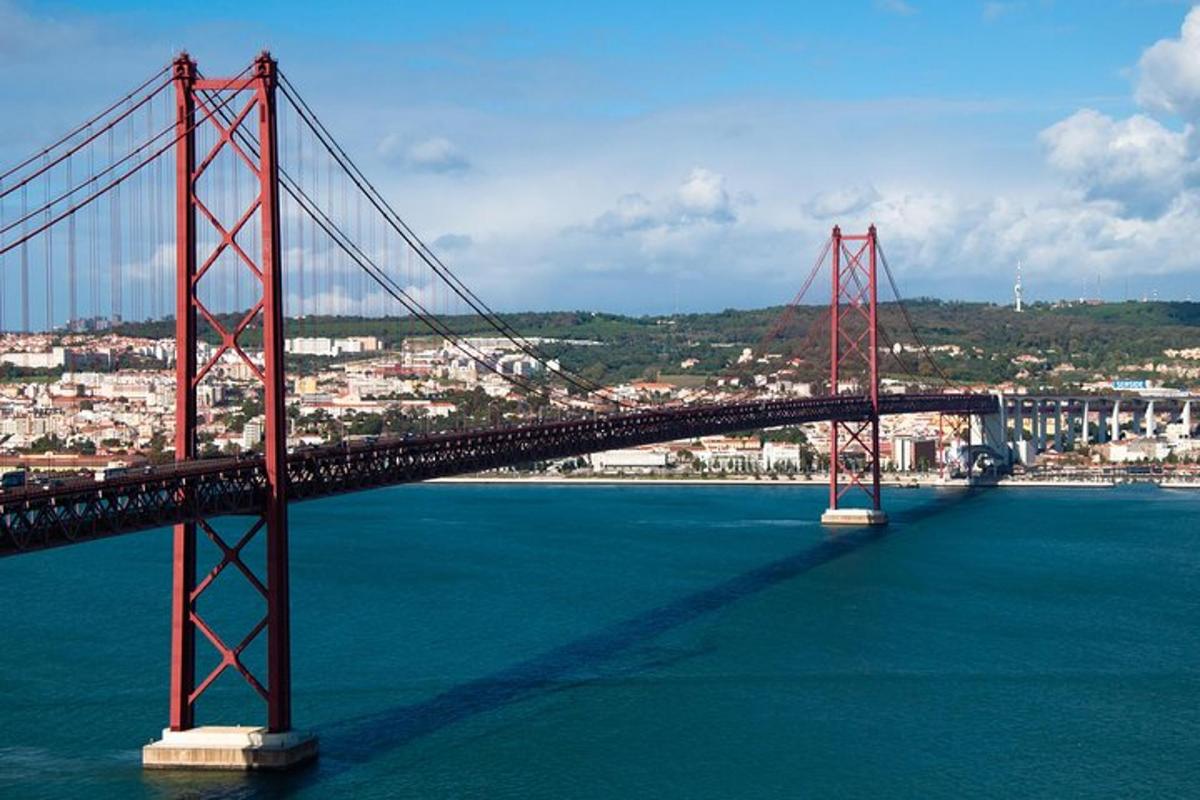 uma grande ponte vermelha sobre a água com uma cidade
