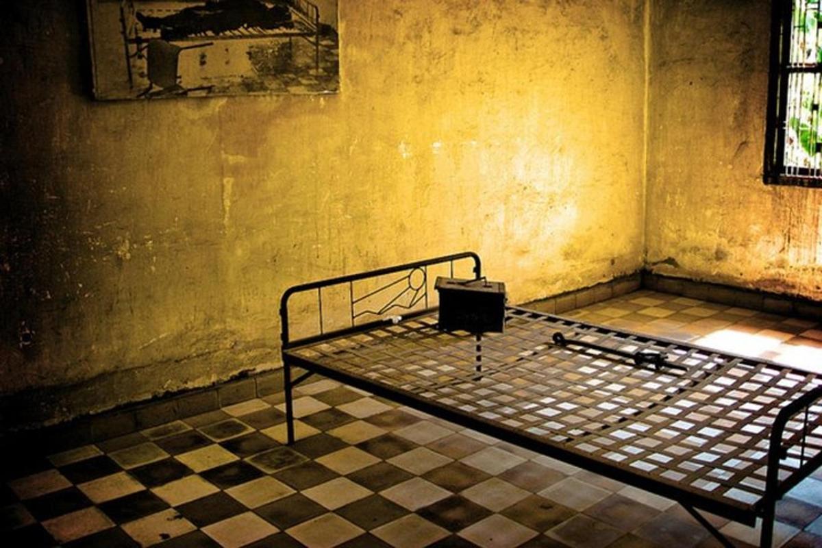 uma cama de metal em um quarto com piso xadrez