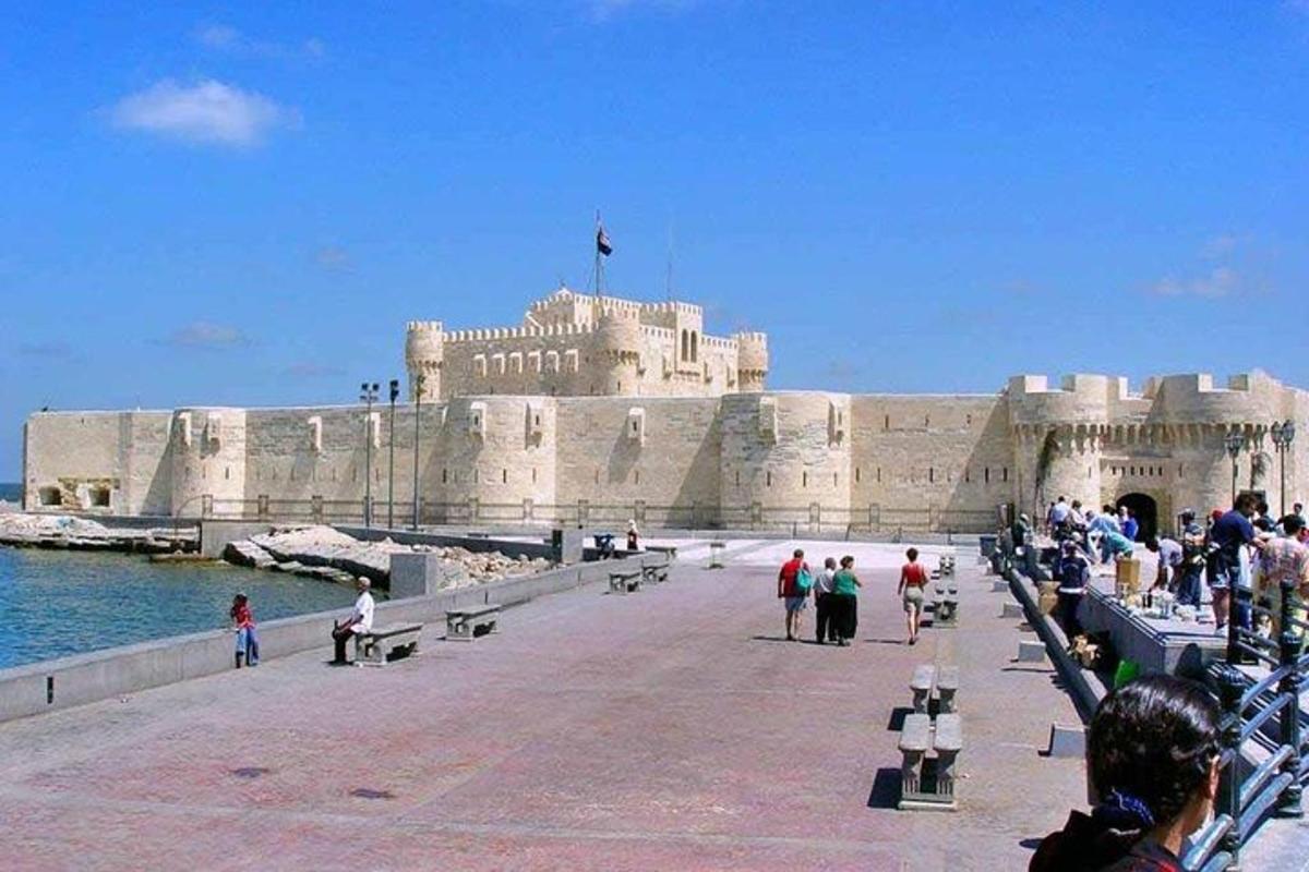 egy csoport ember sétál egy mólón egy épület előtt