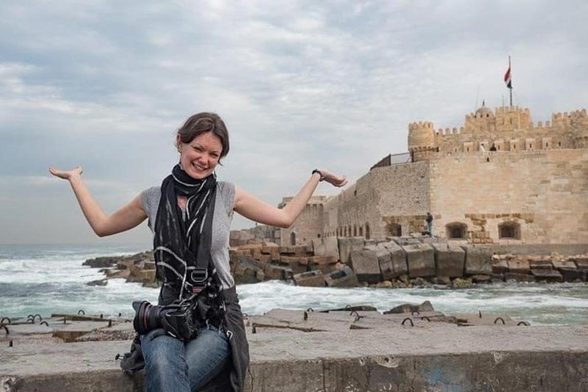 una donna seduta su un muro di fronte a un castello