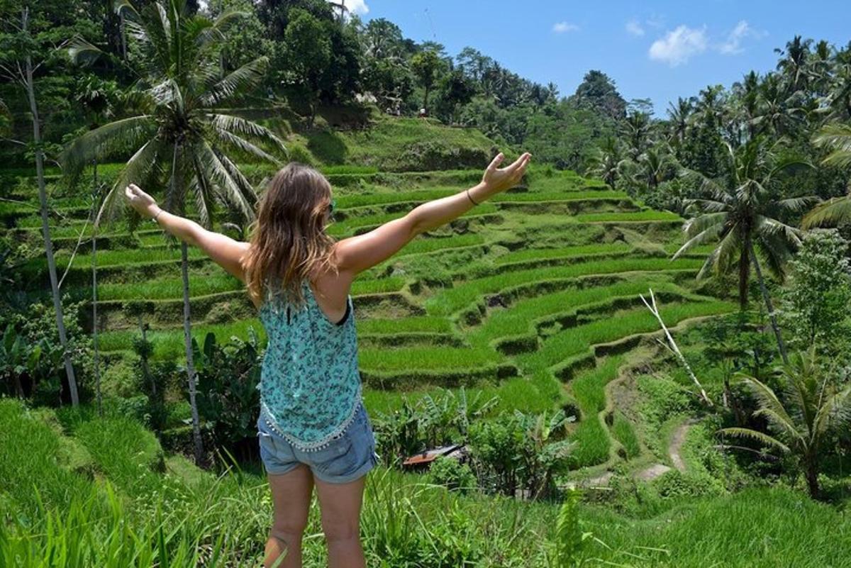 seorang wanita berdiri di atas bukit sambil memandangi sawah
