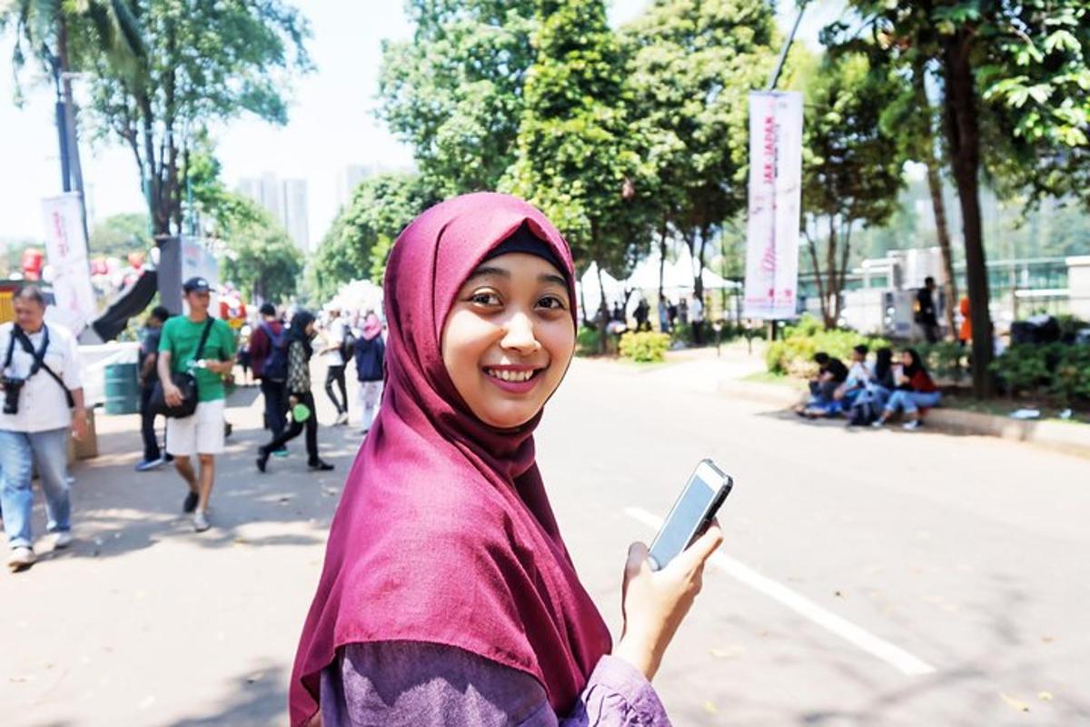 o femeie purtând hijab și ținând în mână un telefon mobil