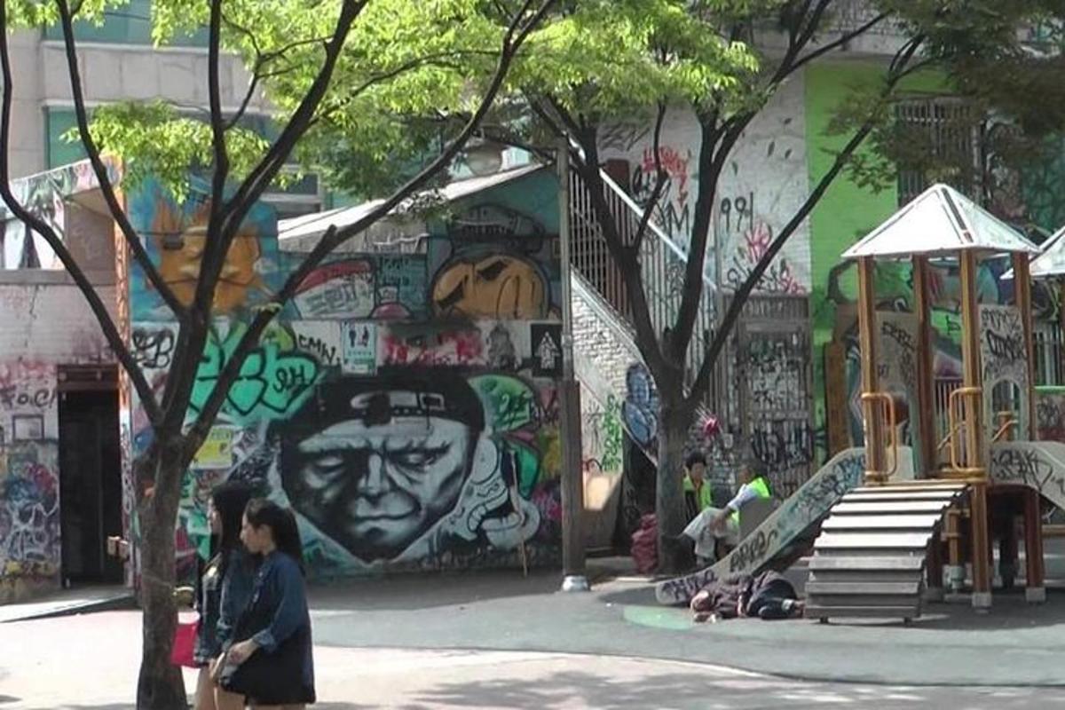 skupina lidí stojících před zdí s graffiti