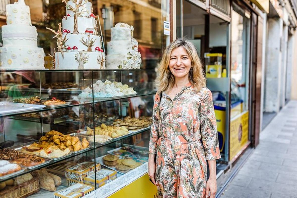 uma mulher parada em frente a uma padaria com bolos