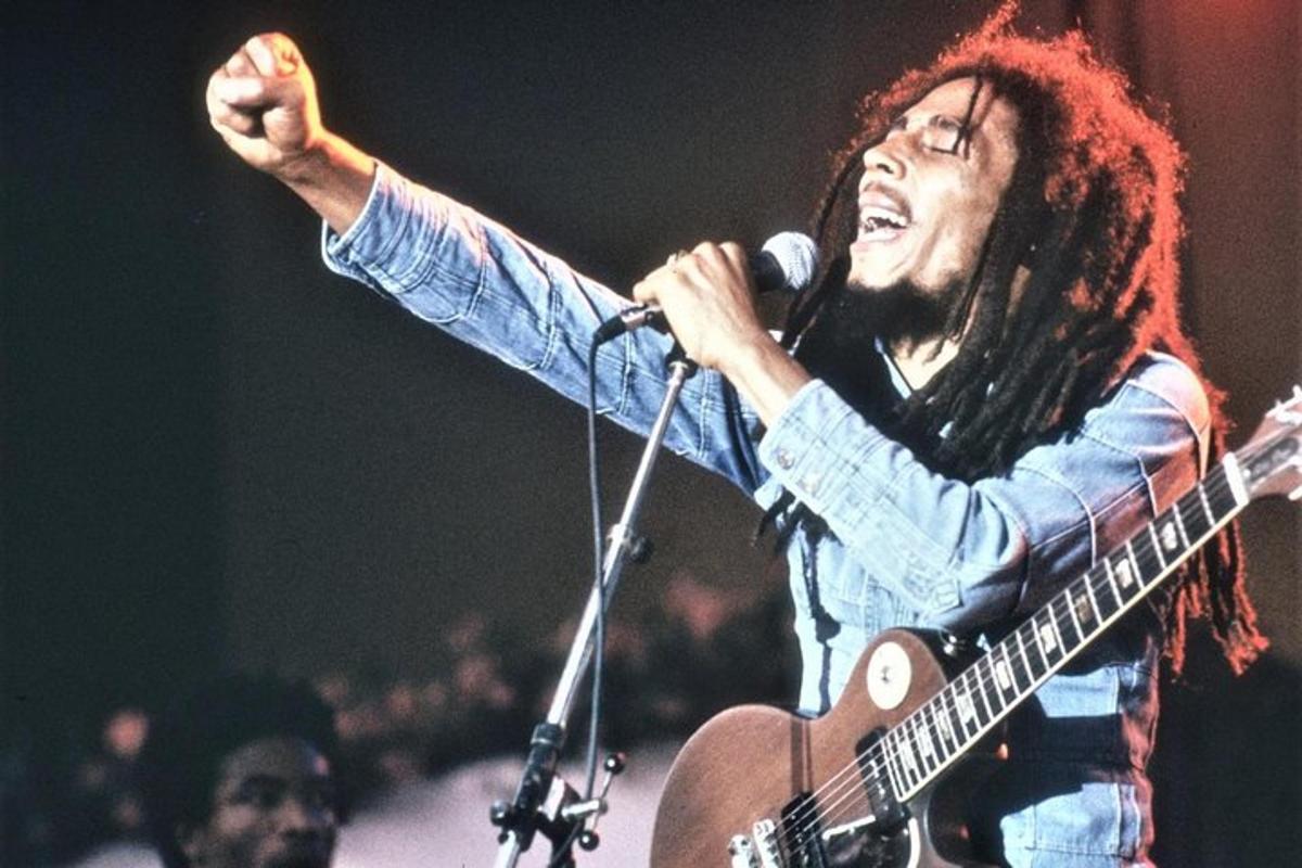 Un hombre con pelo largo tocando una guitarra con un micrófono.