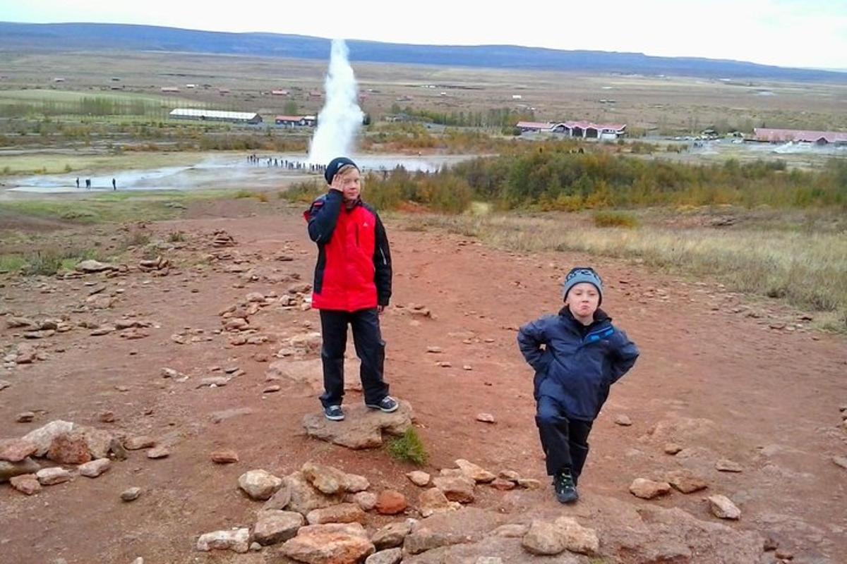 dois homens estão parados em uma estrada de terra com um gêiser