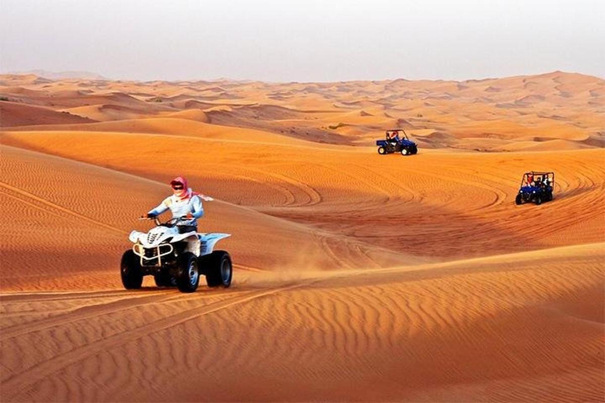 três pessoas andando de quadriciclo no deserto