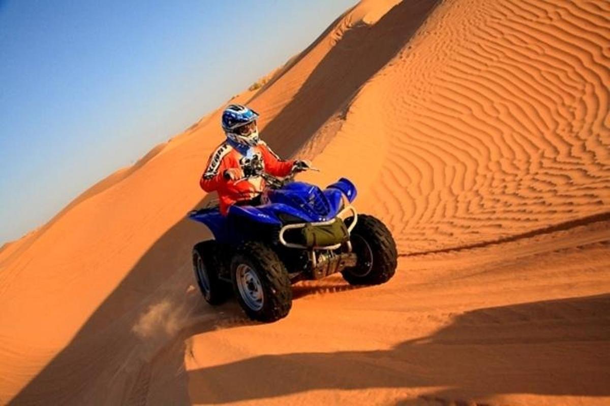uma pessoa andando de quadriciclo em uma duna de areia