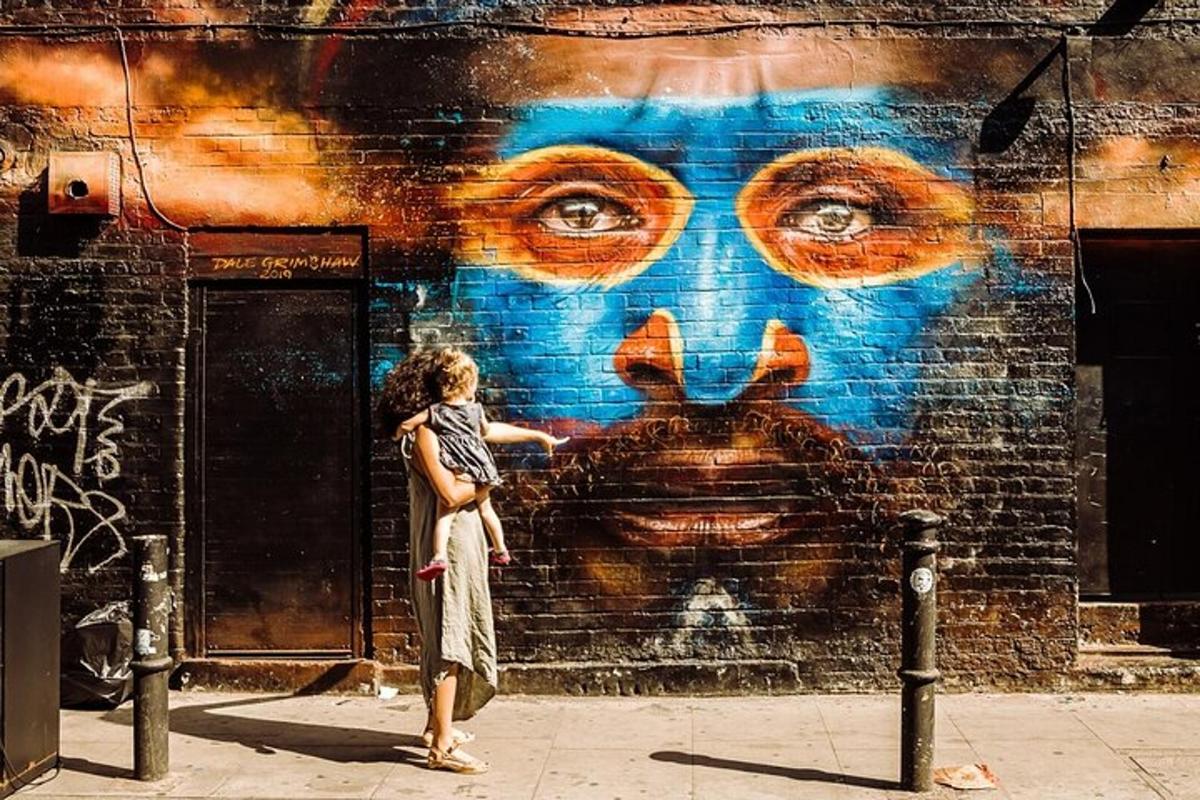Una mujer parada frente a una pared con un mural.
