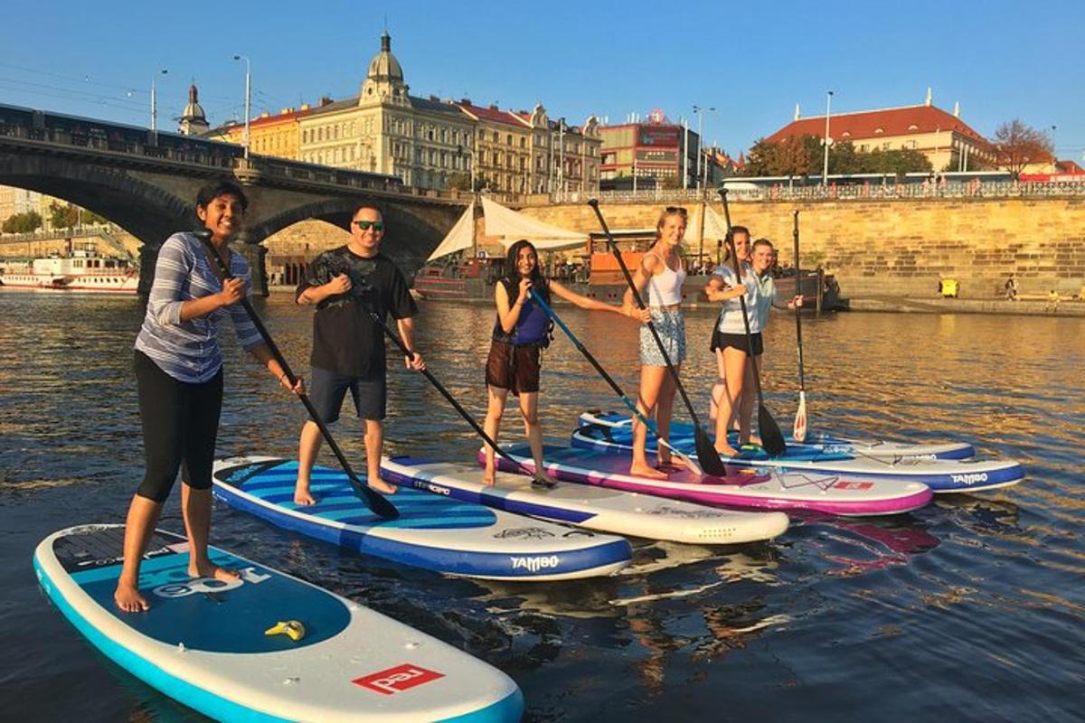skupina lidí stojících na paddleboardech ve vodě