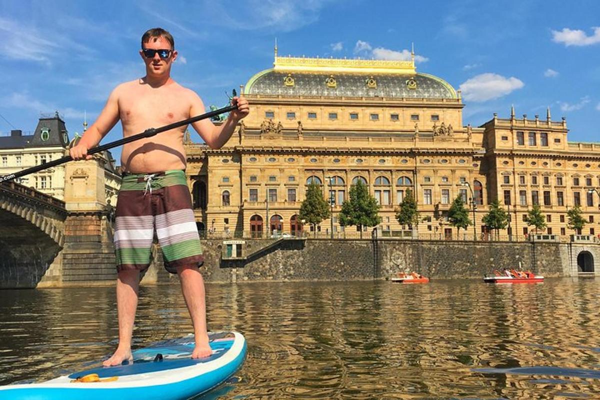 Muž stojí na paddleboardu ve vodě