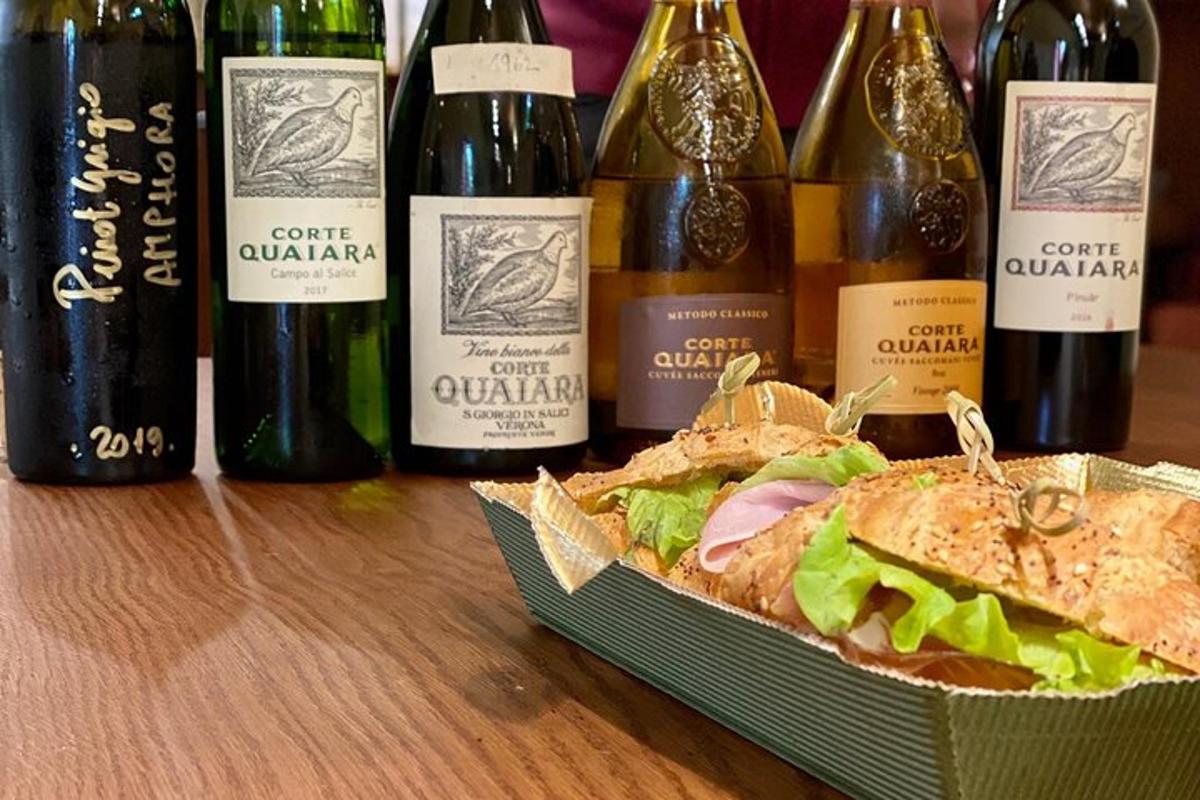 Un sándwich en una caja junto a botellas de vino.