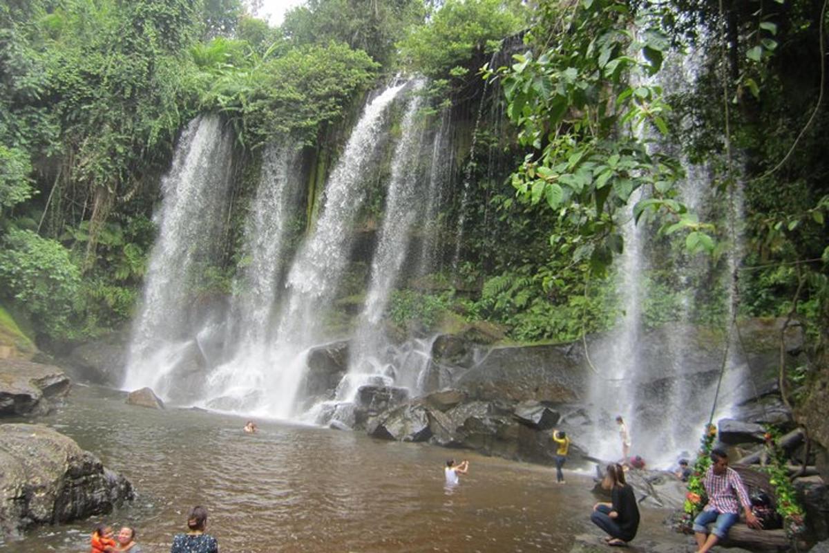 un gruppo di persone in acqua davanti a una cascata
