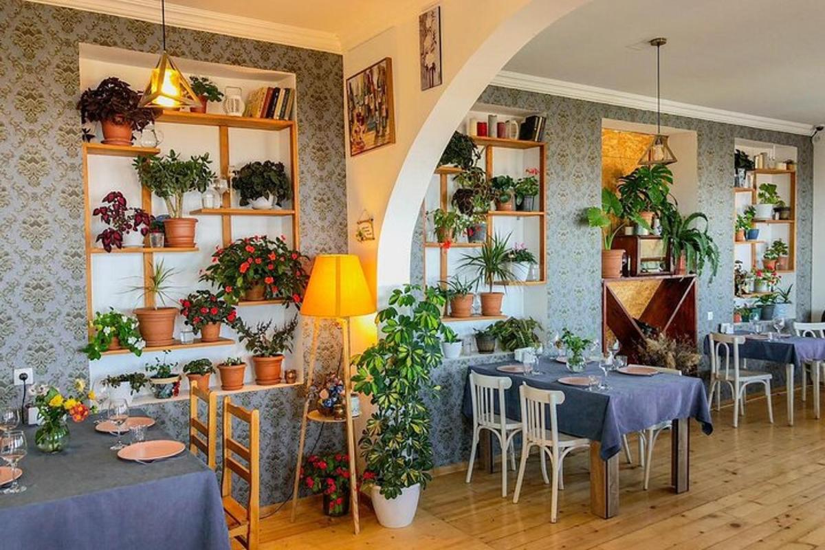restorāns ar galdiem un augiem pie sienām