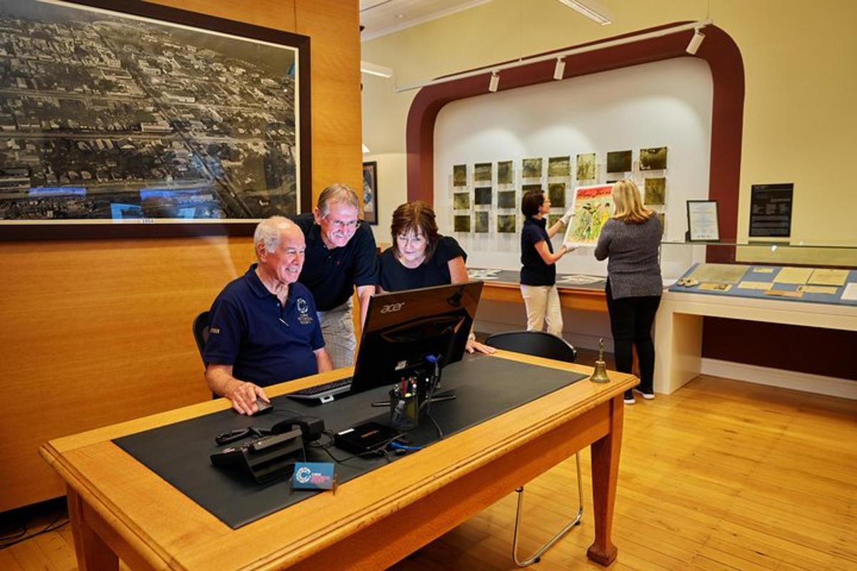 a group of people standing around a table with a laptop
