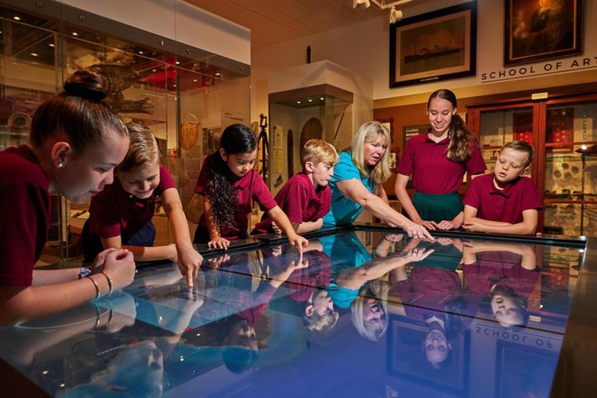 a group of children and a woman looking at a glass table