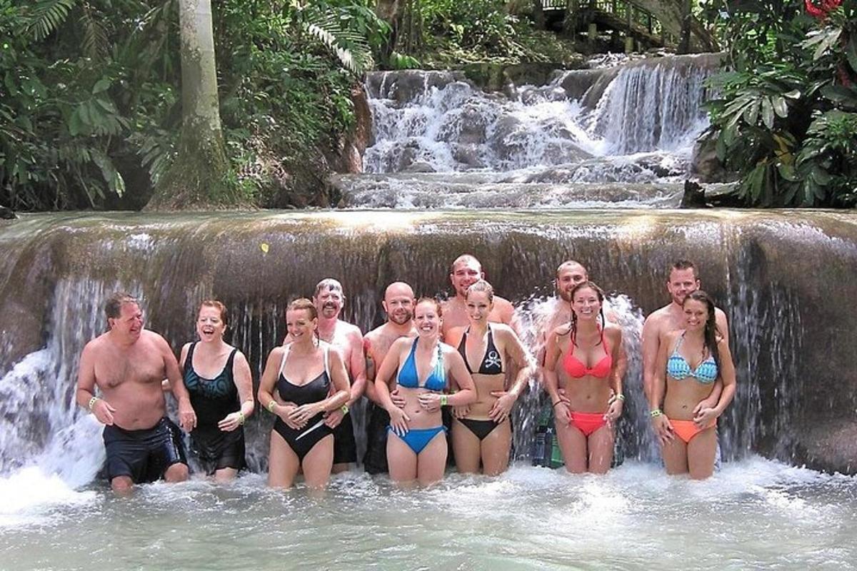 um grupo de pessoas em pé em frente a uma cachoeira