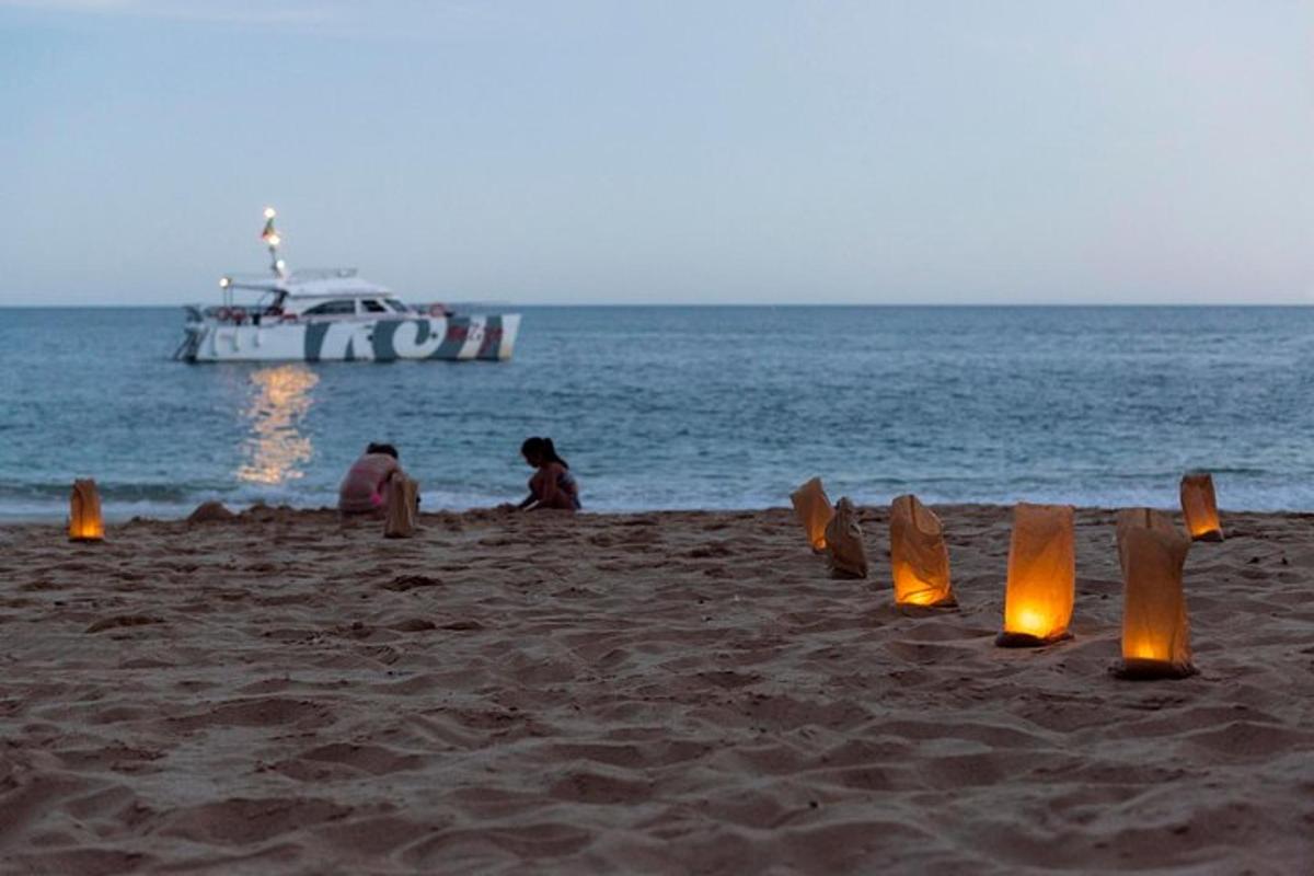 Un grupo de personas sentadas en una playa con un bote.
