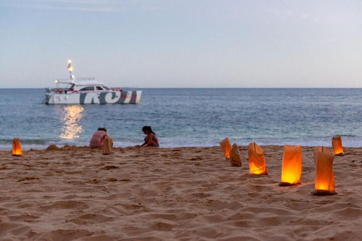 Dos personas sentadas en una playa con un bote en el agua
