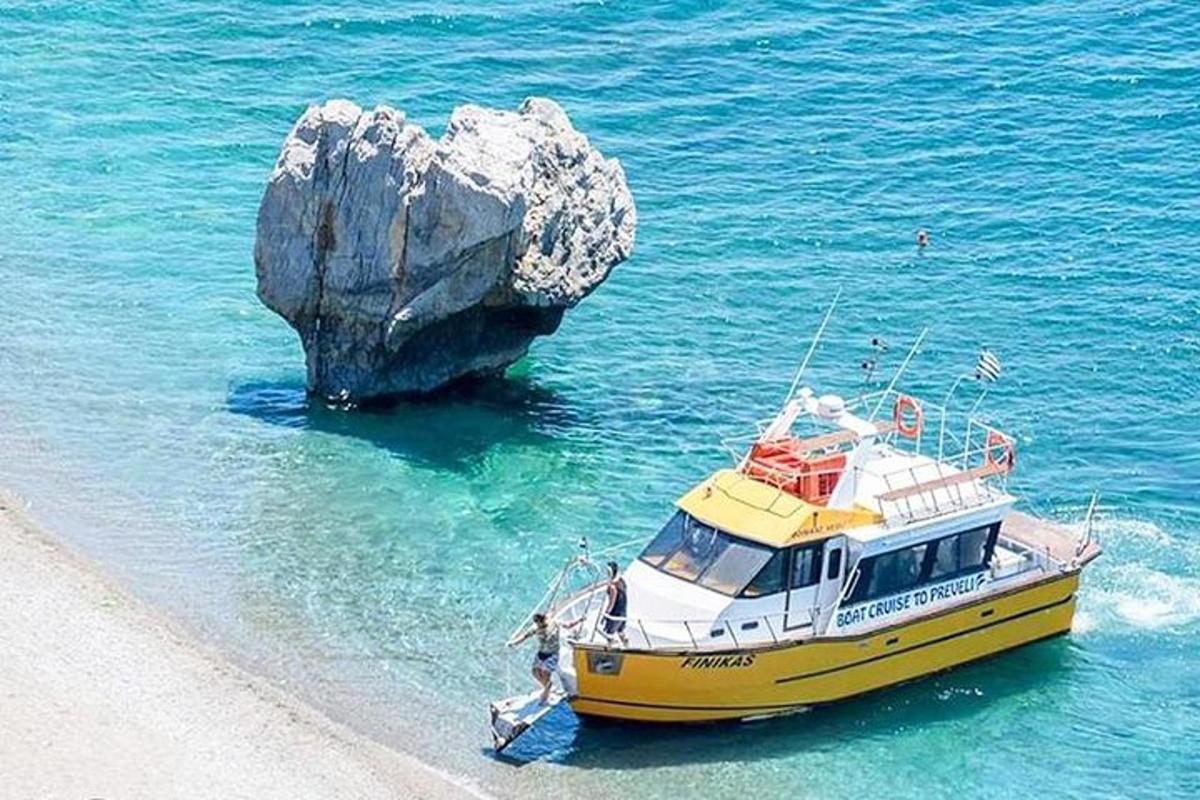 a yellow and white boat in the water next to a rock