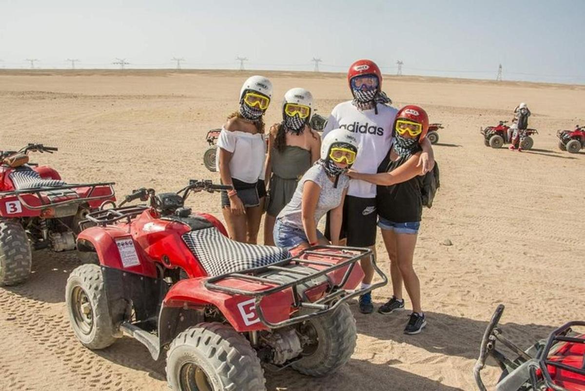 sekumpulan orang berdiri di padang pasir dengan atv