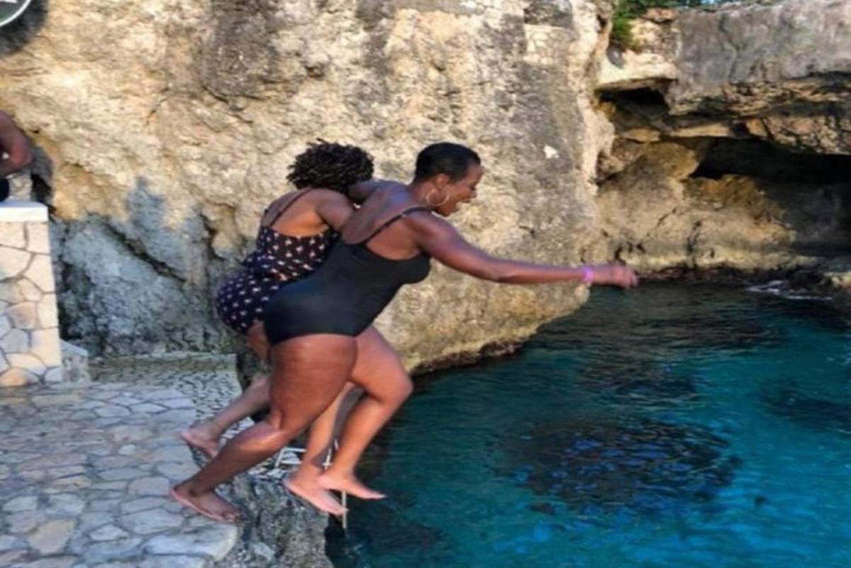 Dos personas de pie sobre una roca cerca de un estanque de agua.