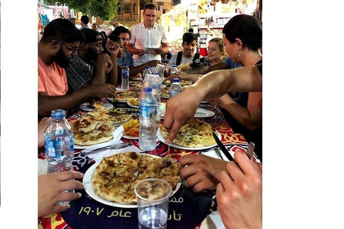 a group of people sitting around a table eating pizza