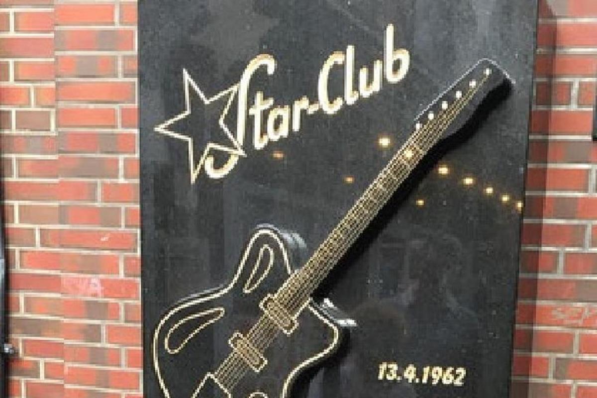 Una imagen de una guitarra en el costado de un edificio.