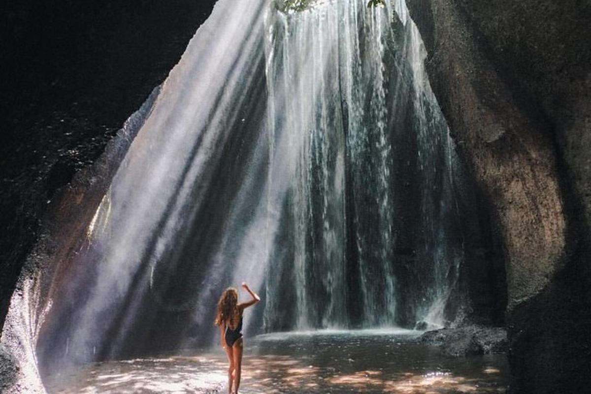 uma mulher parada em frente a uma cachoeira