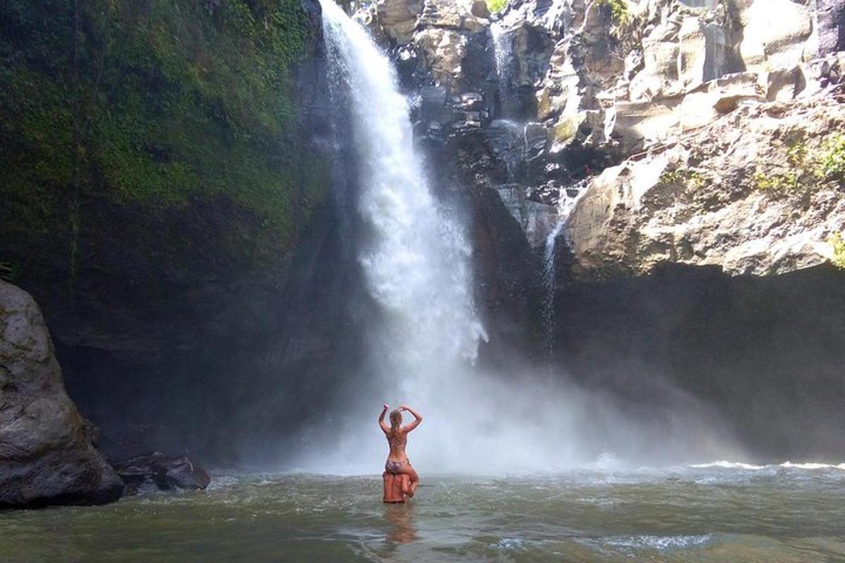 uma mulher parada na água em frente a uma cachoeira