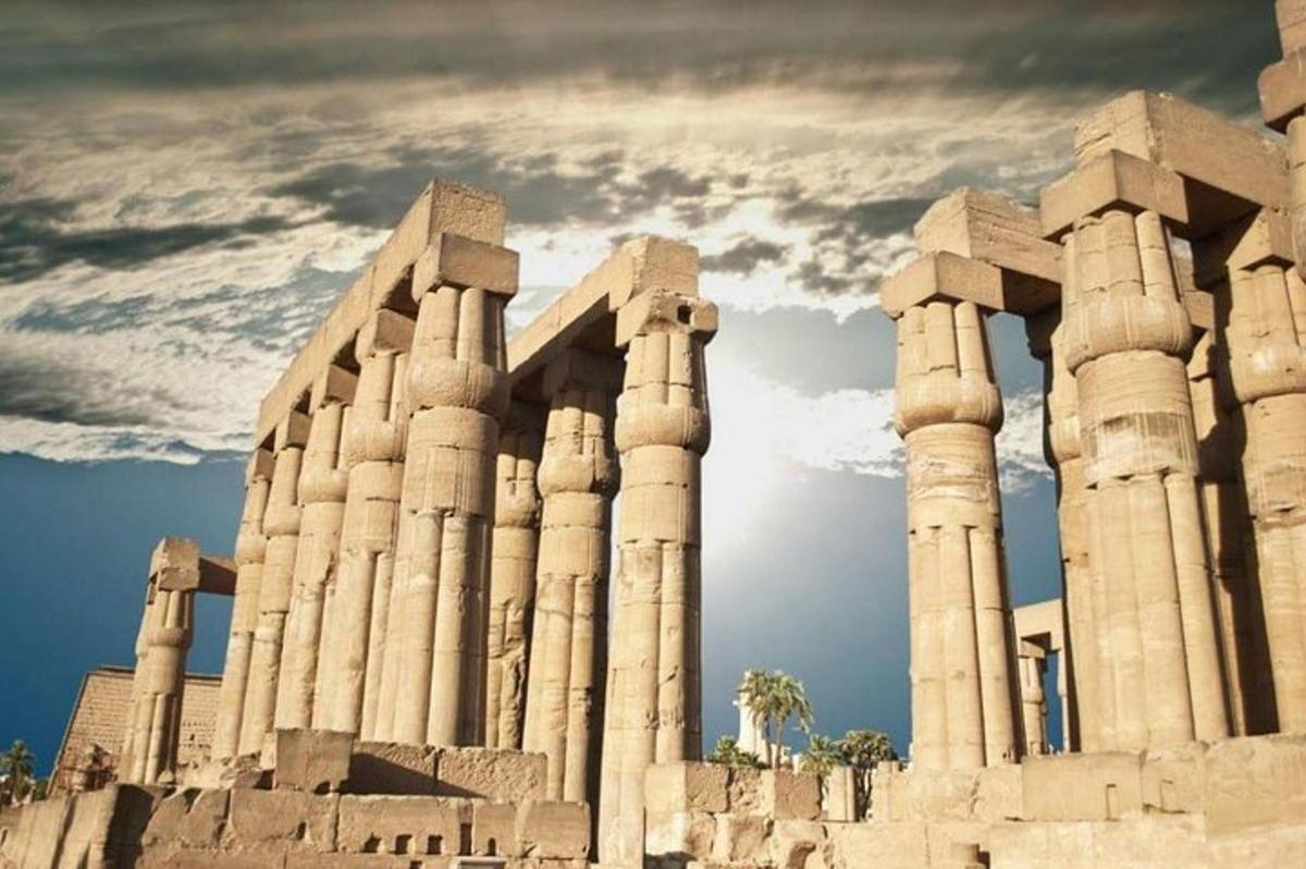 un antico edificio con colonne e un cielo nuvoloso