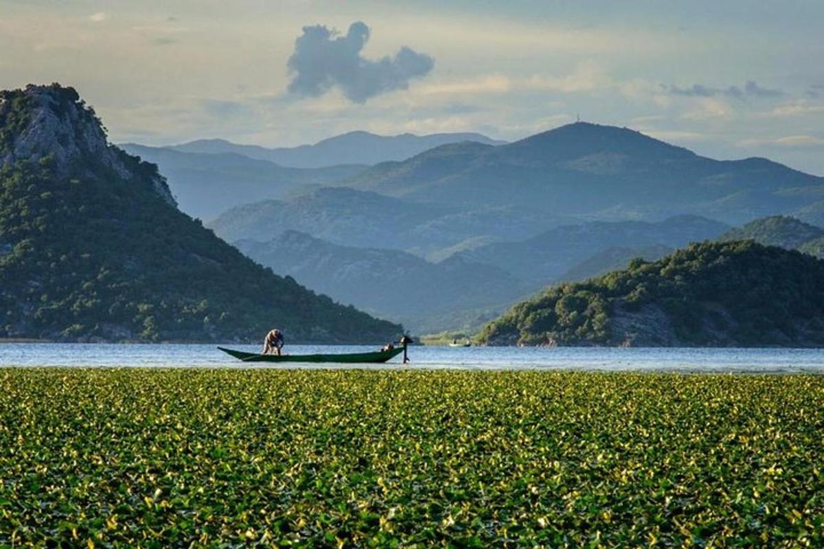 un uomo in una barca sull'acqua con le montagne