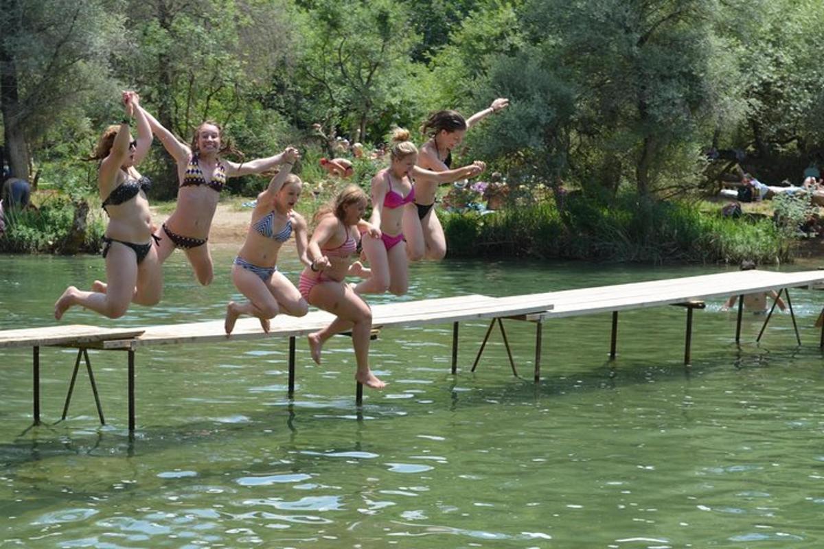 a group of girls jumping off a beam in the water