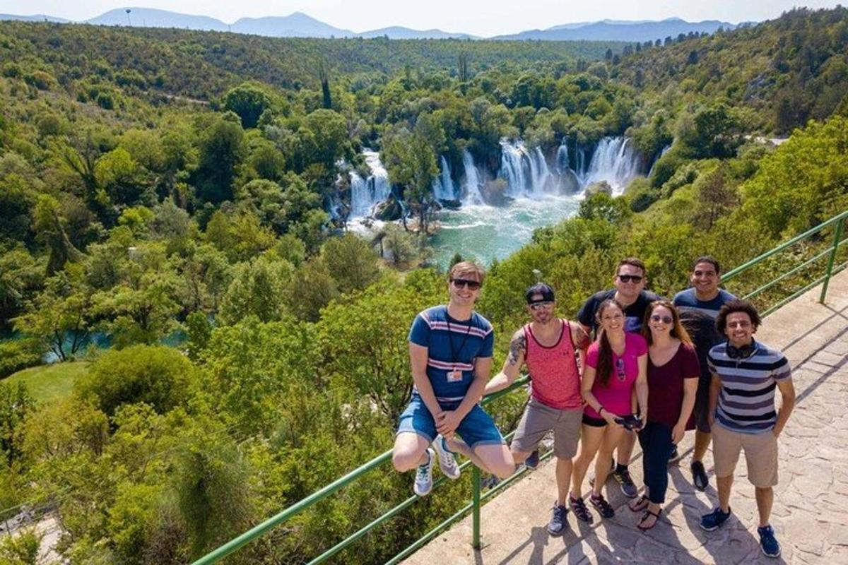 a group of people standing on a suspension bridge in front of waterfall