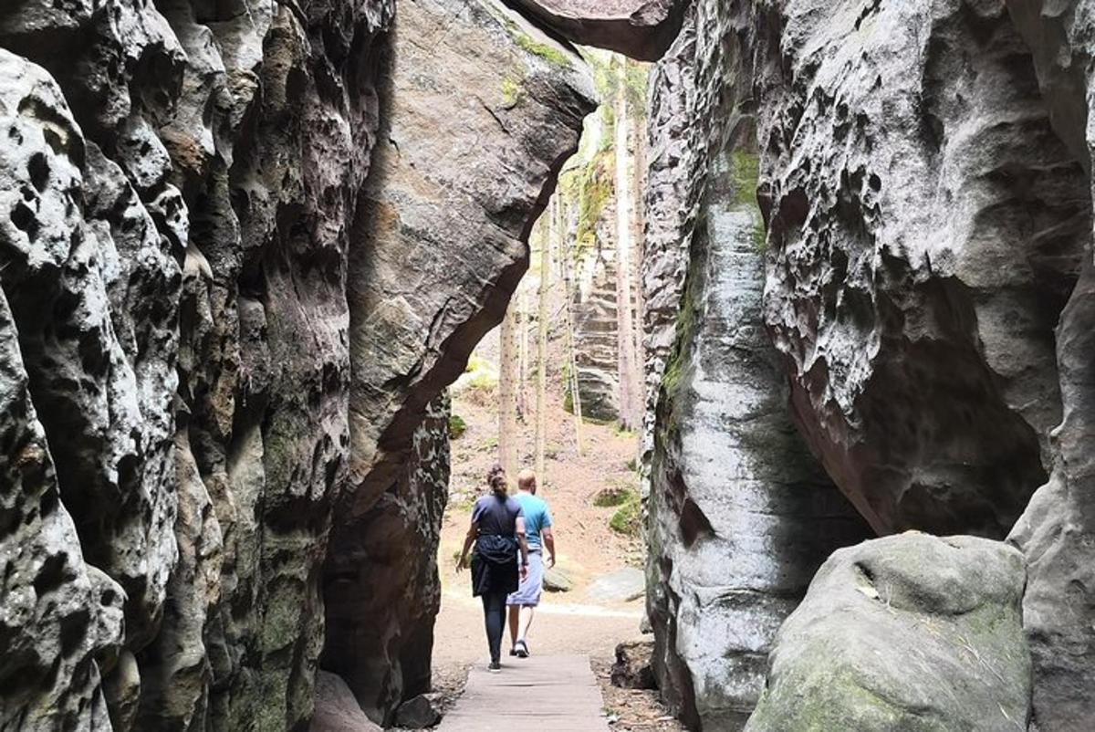 Dos personas caminando por un sendero a través de una pared de roca.
