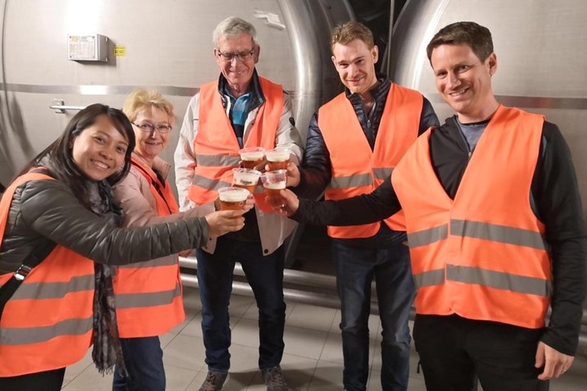 Un grupo de personas con chalecos naranjas sosteniendo bebidas.