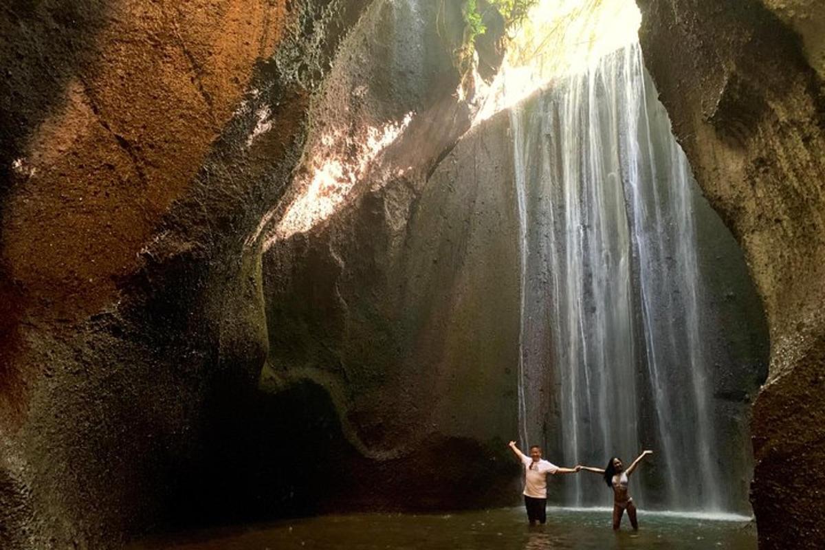 due persone in piedi nell'acqua di fronte a una cascata