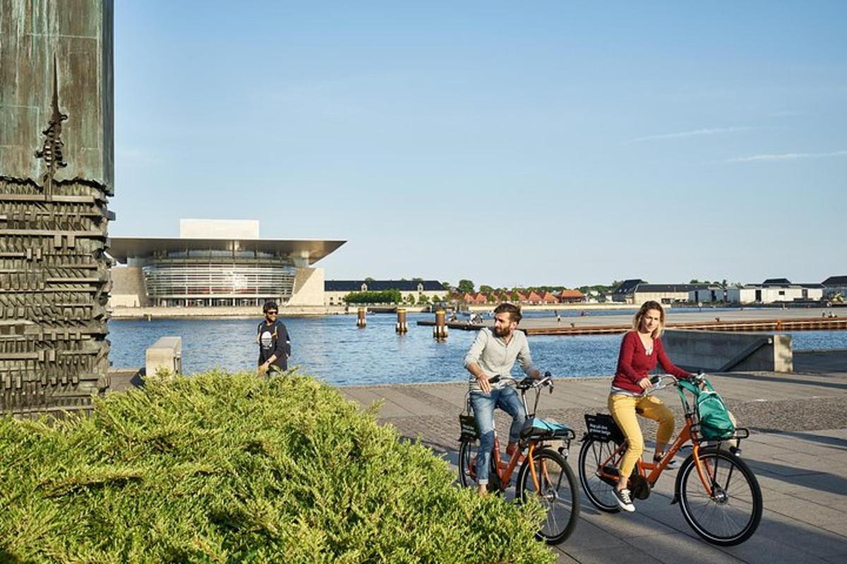 two people riding bikes on a sidewalk next to a river