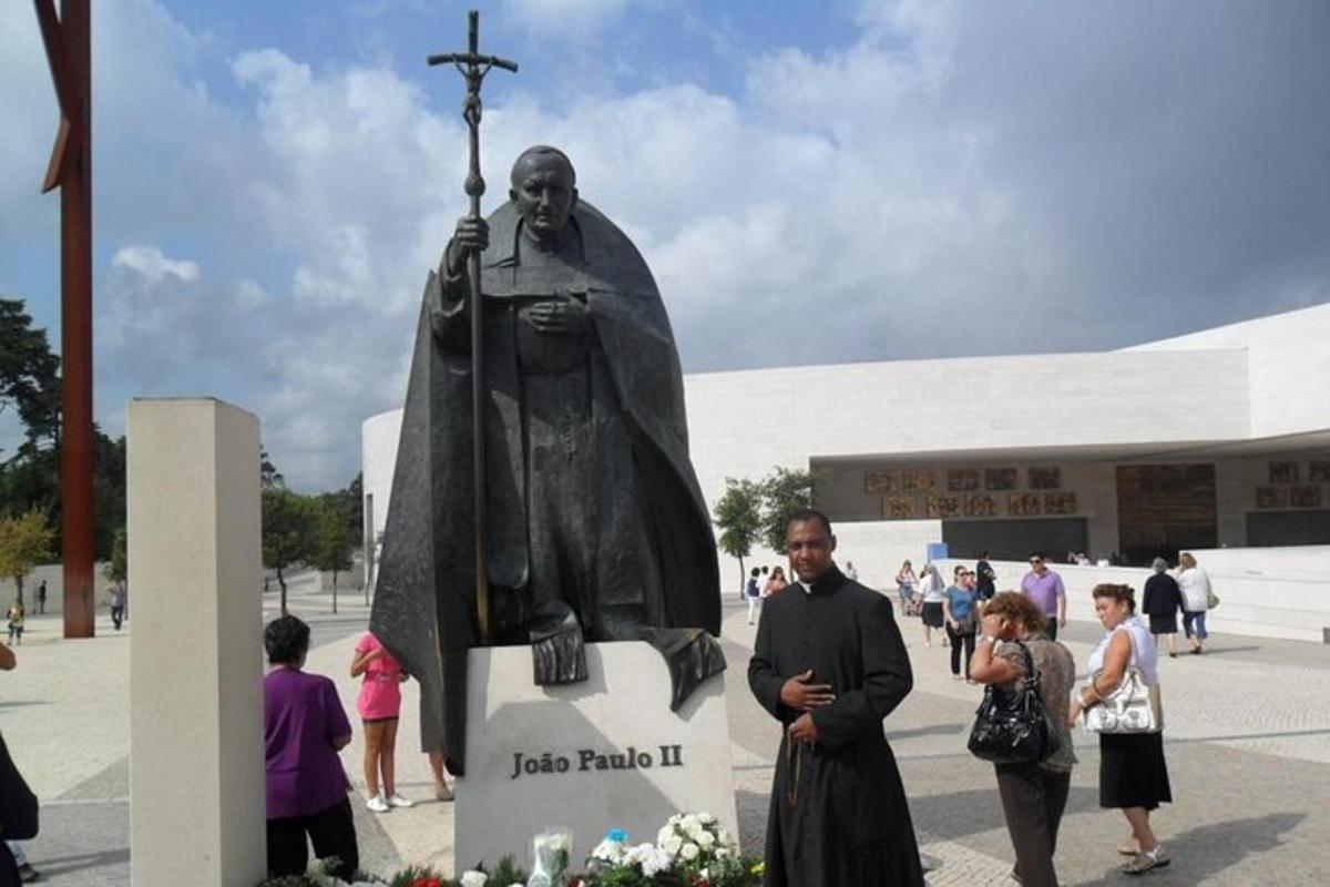Un hombre parado frente a una estatua de un predicador.