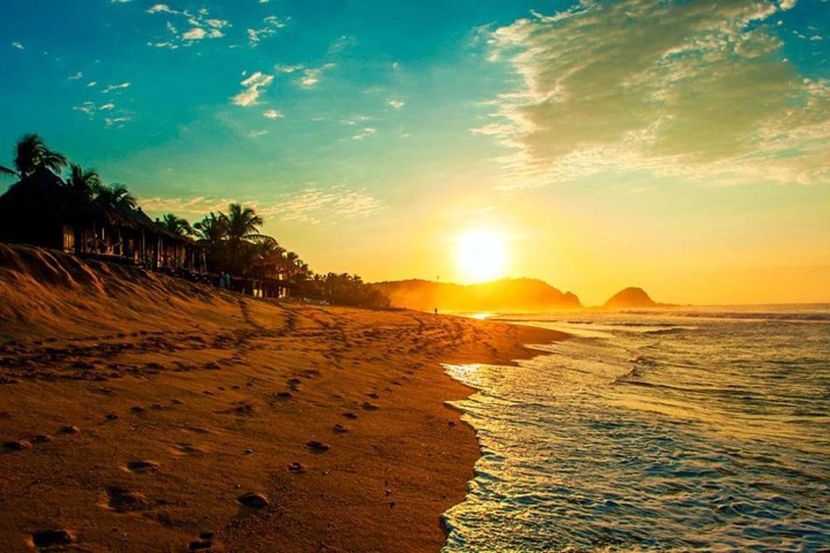 a beach with the sun setting in the distance