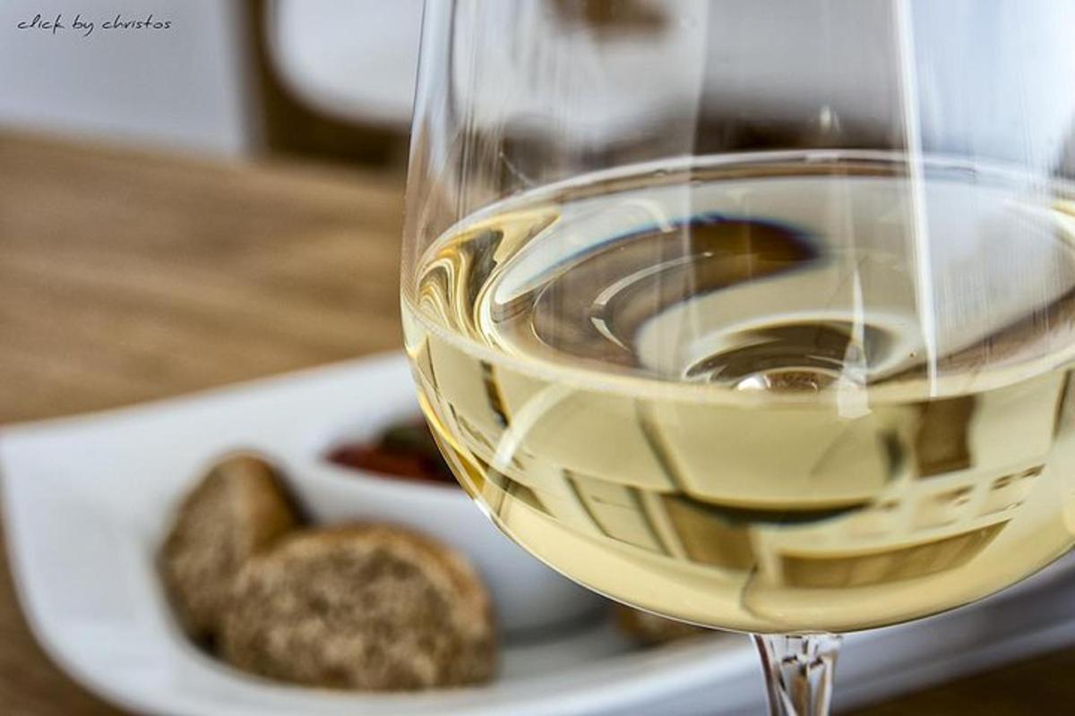 uma taça de vinho branco ao lado de um prato de comida