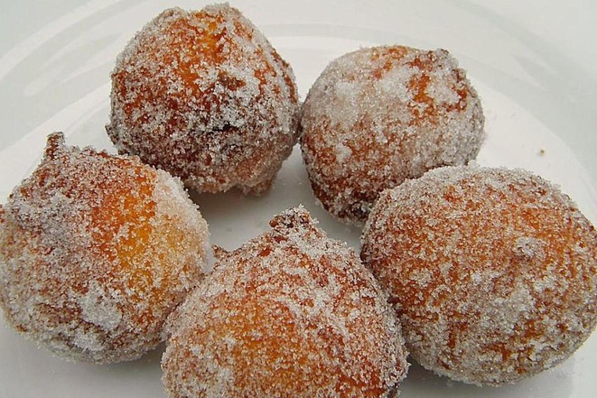 Cuatro donas cubiertas de azúcar en un plato blanco