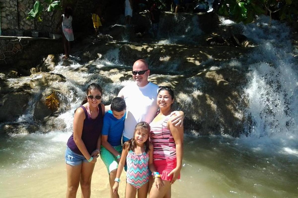 sebuah keluarga berdiri di pantai di hadapan air terjun