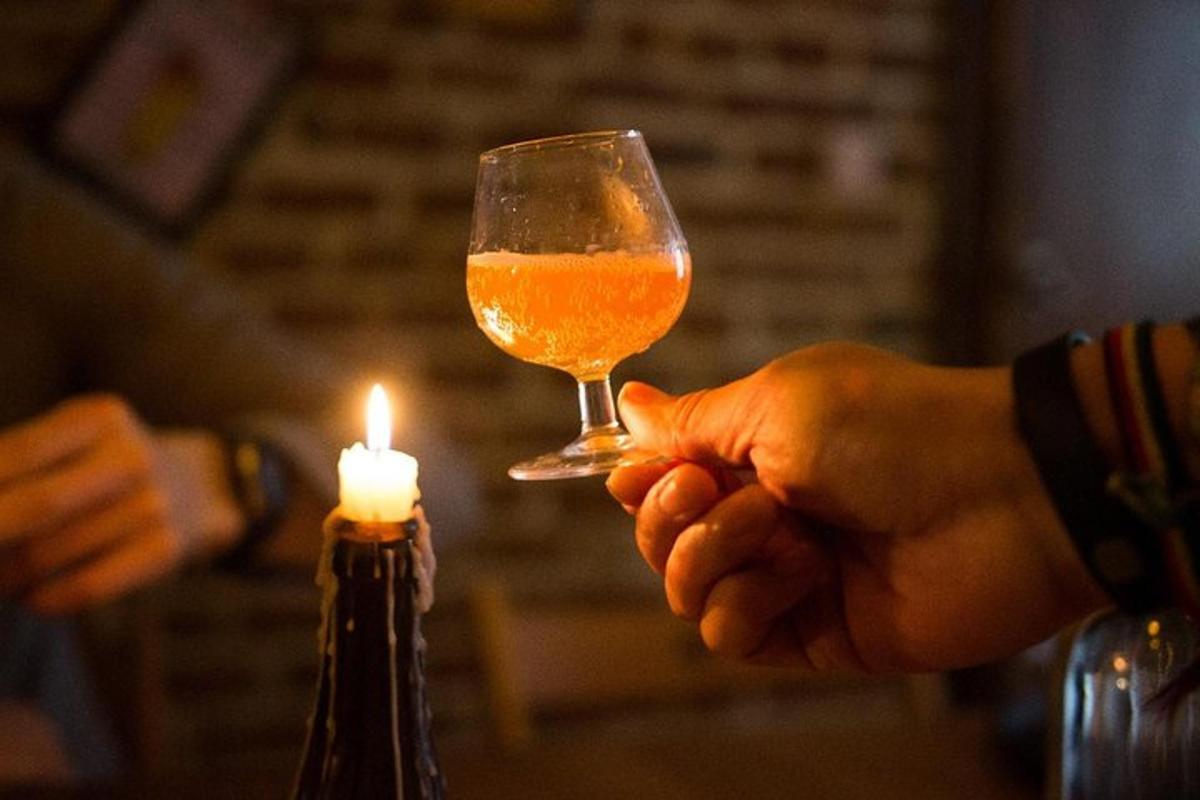 osoba držící sklenici piva a svíčku