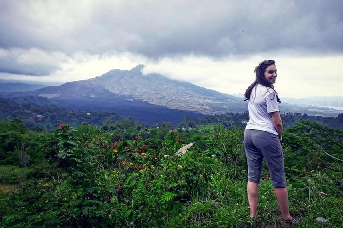 a woman standing on a hill with a mountain in the background