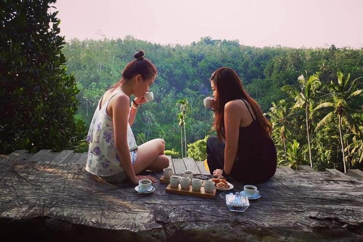 two women sitting on a rock with a table of food