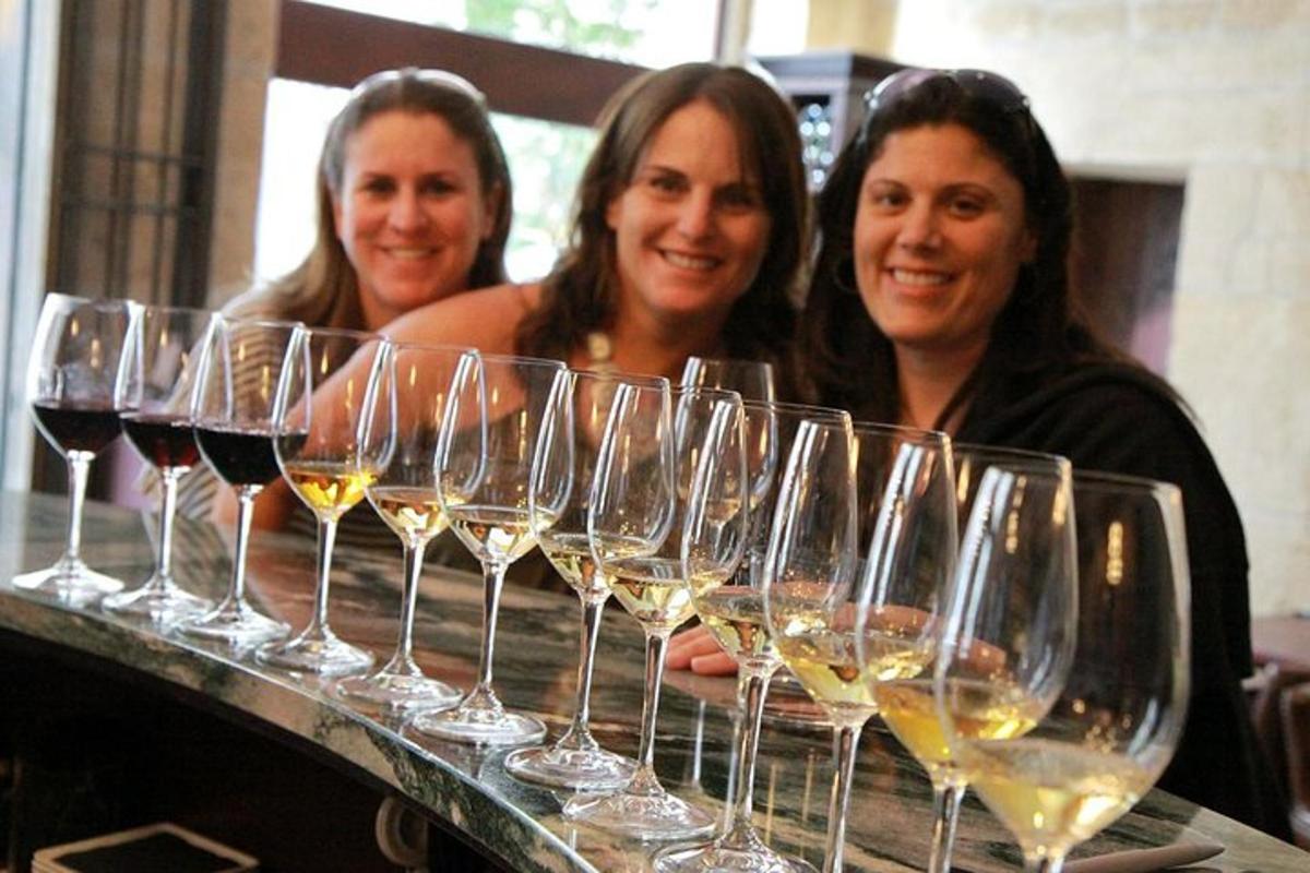 tres dones dempeus davant d'una filera de copes de vi