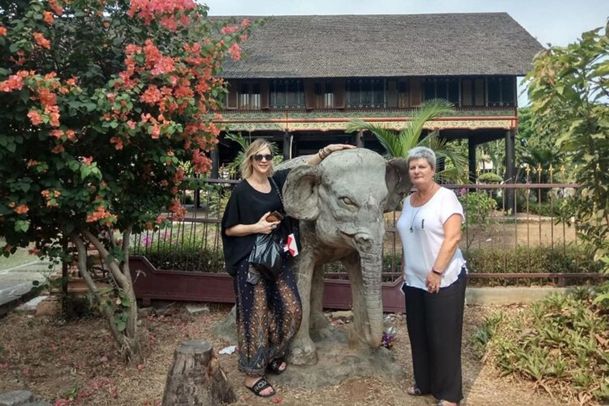 duas mulheres em pé ao lado de uma estátua de um elefante