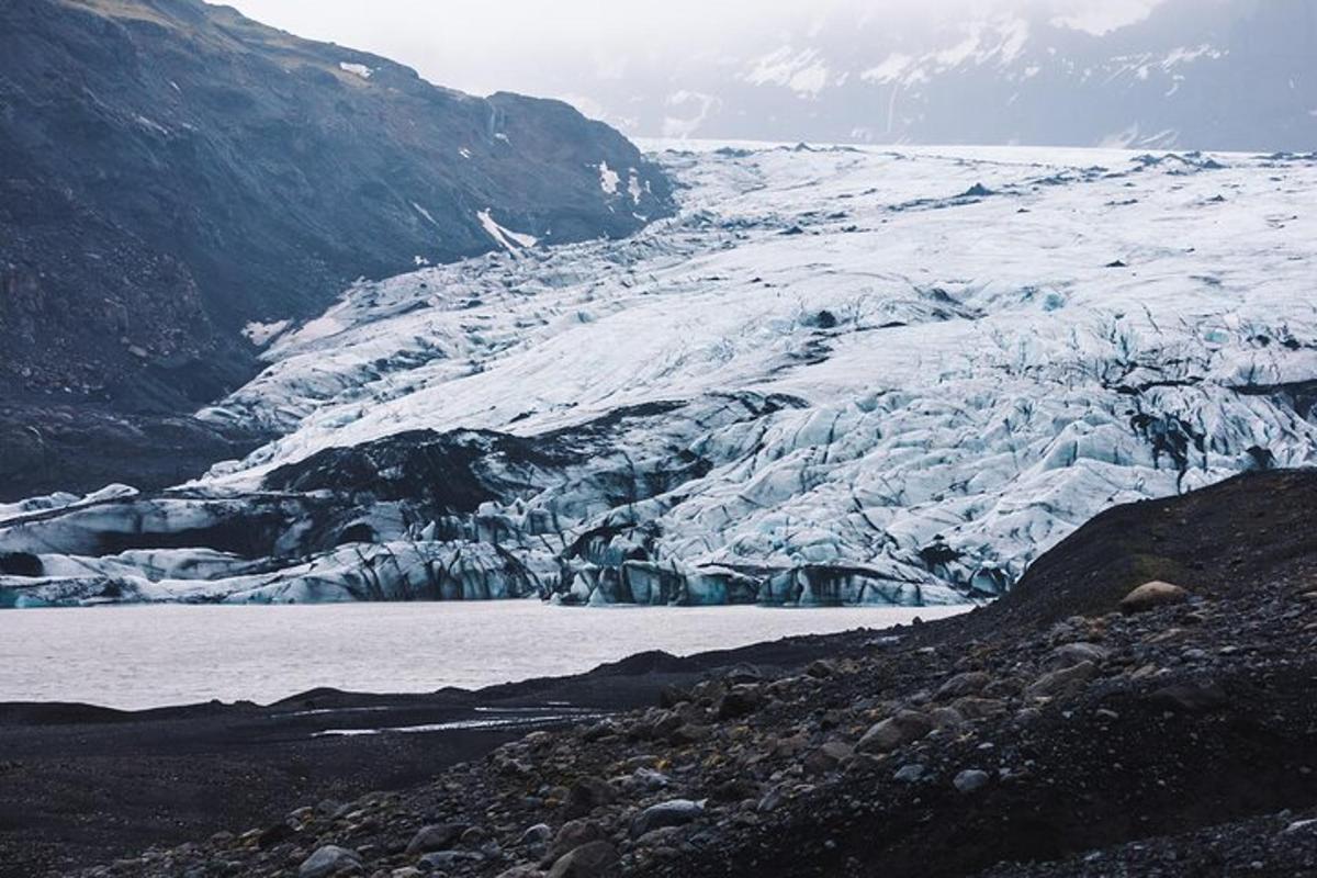 un ghiacciaio con uno specchio d'acqua accanto a una montagna